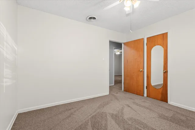 an empty room with windows and chandelier fan