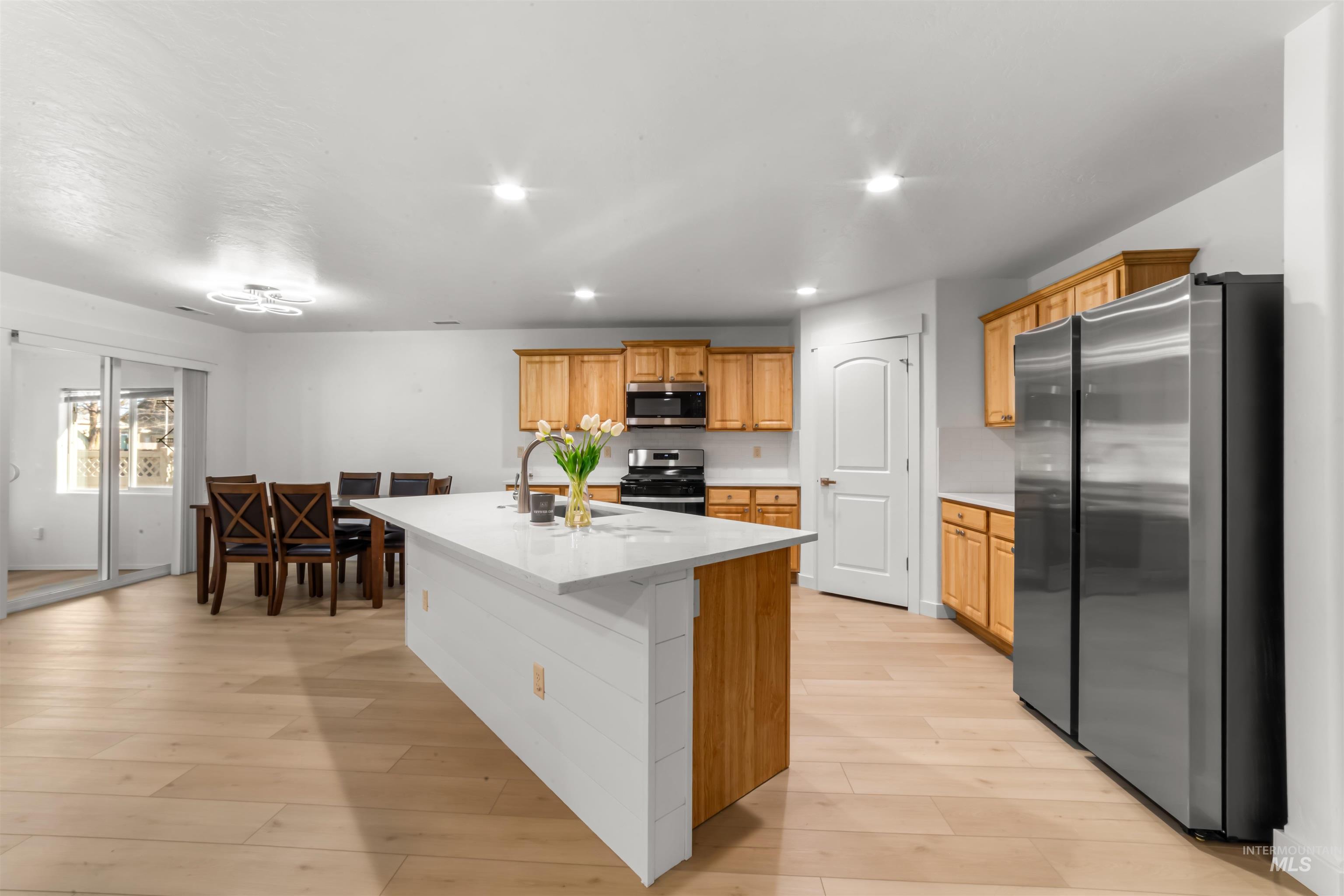 548 North Ripplerock Place Star, ID 83669 - Photo 19 of 42 Kitchen featuring stainless steel appliances, a center island with sink, recessed lighting, light wood-type flooring, and light stone countertops