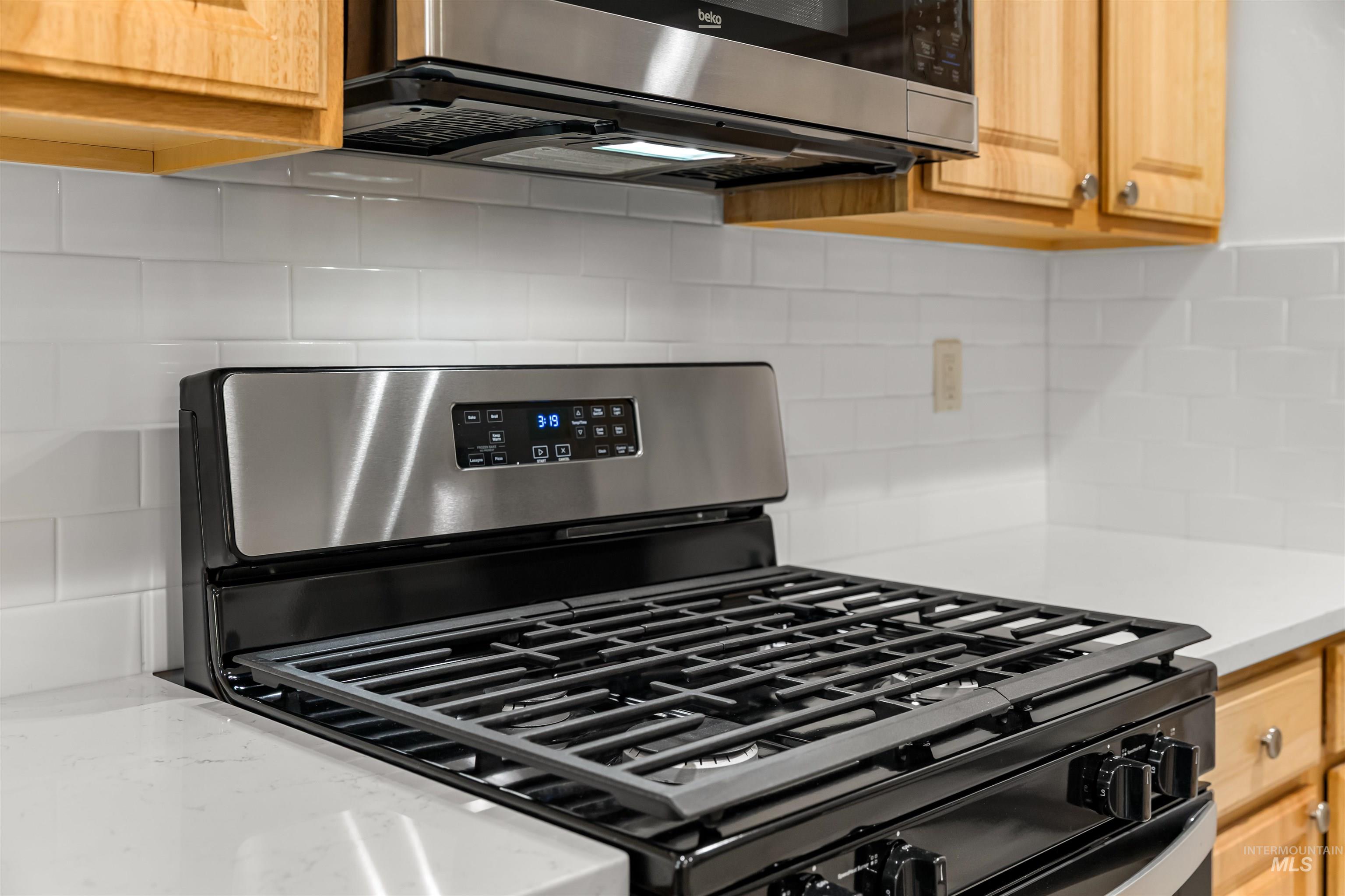 548 North Ripplerock Place Star, ID 83669 - Photo 39 of 42 Kitchen featuring stainless steel appliances, decorative backsplash, and light stone counters