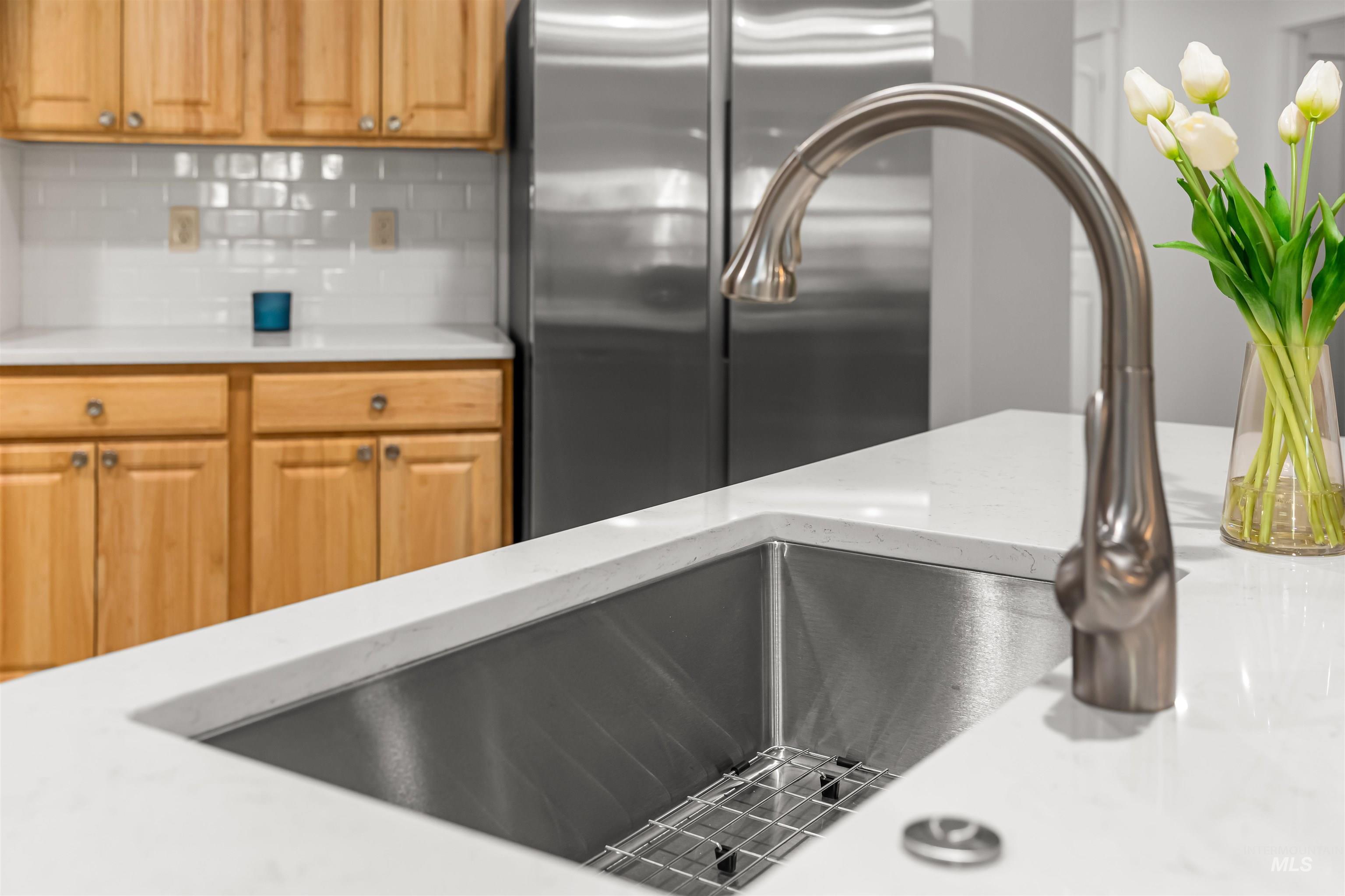 548 North Ripplerock Place Star, ID 83669 - Photo 40 of 42 Kitchen with freestanding refrigerator, backsplash, and light stone countertops