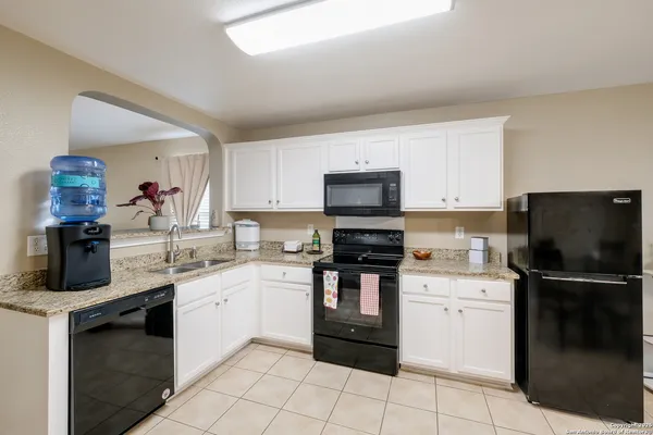 a kitchen with a sink white cabinets and stainless steel appliances