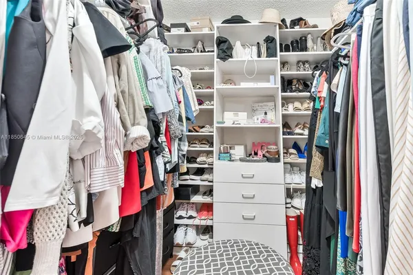 a view of walk in closet with clothes and shoes