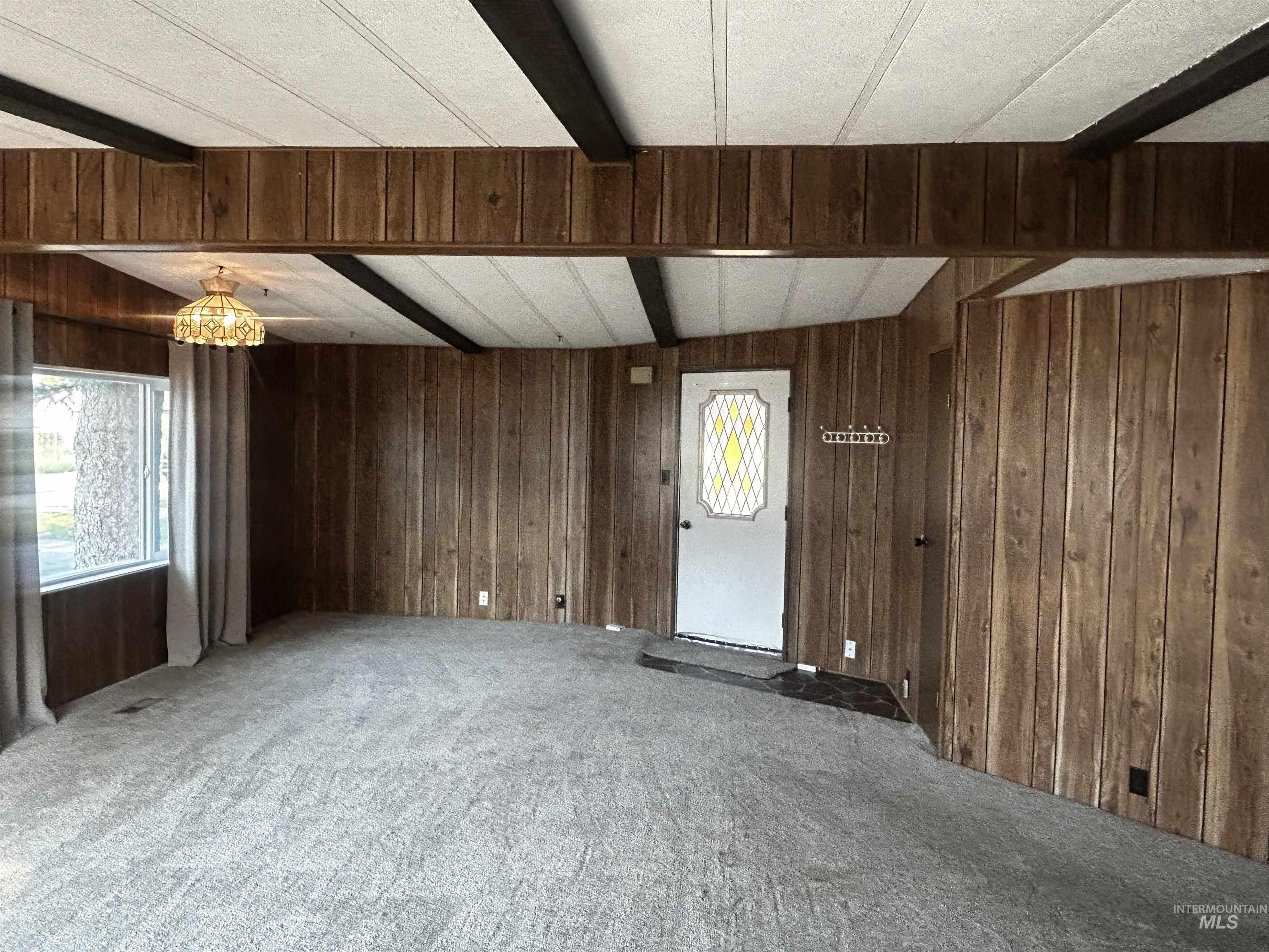 10165 West Claudia Road Boise, ID 83714 - Photo 12 of 30 Wood-finish wall paneling, white paneled ceiling with dark beams, and a window with a built-in valance