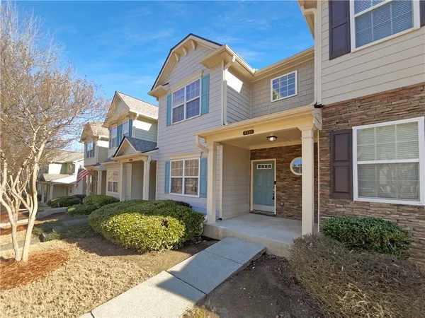 a view of a brick house with large windows next to a yard