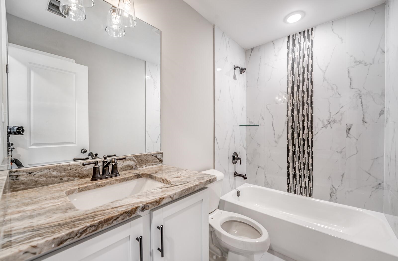 60 Umble Street Oakland, TN 38060 - Photo 29 of 40 a bathroom with a granite countertop sink a toilet a mirror a bathtub and shower