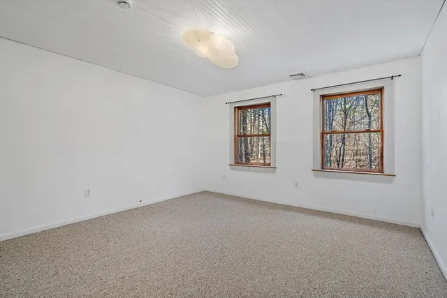 an empty room with windows and chandelier fan