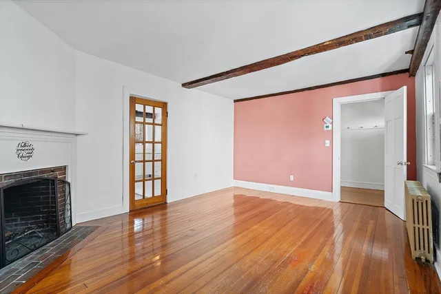 an empty room with wooden floor fireplace and windows