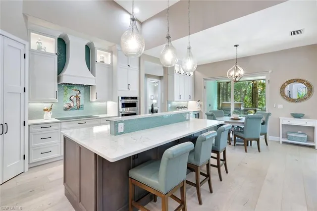 a kitchen with kitchen island a dining table chairs sink and cabinets