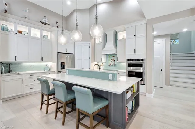 a kitchen with kitchen island a dining table chairs cabinets and a sink