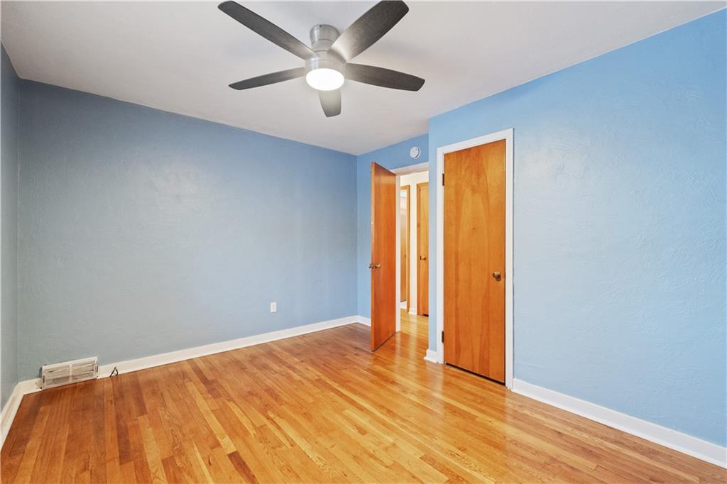 903 Wible Run Road Pittsburgh, PA 15209 - Photo 16 of 33 an empty room with wooden floor and a ceiling fan