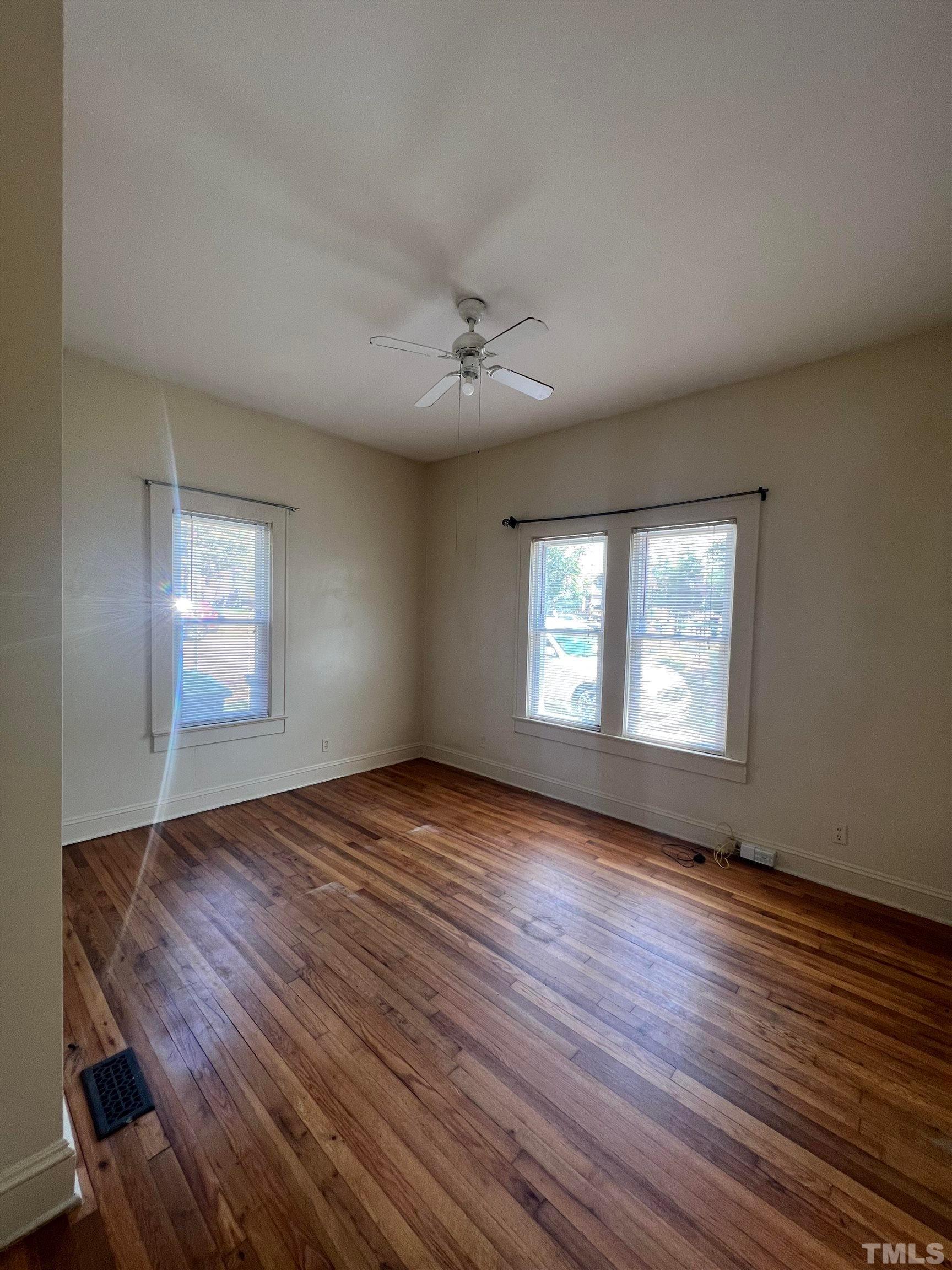 9 Dixie Trail Raleigh, NC 27607 - Photo 10 of 14 an empty room with wooden floor chandelier fan and windows