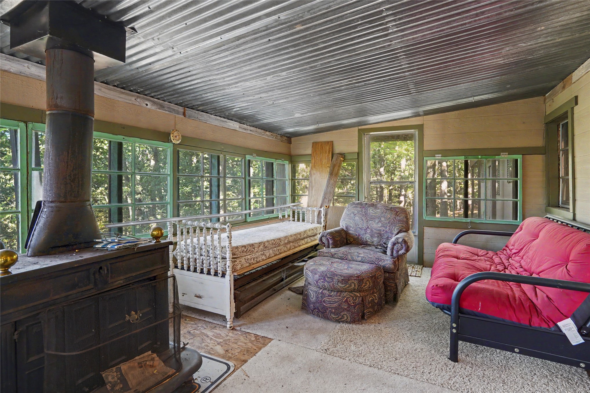 46420 South 590 Road Jay, OK 74346 - Photo 45 of 63 Corrugated metal ceiling, prominent wood-burning stove, numerous multi-pane windows, and a carpeted floor
