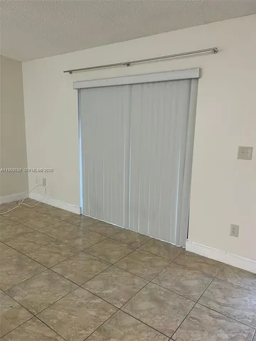 an empty room with a chandelier fan and windows