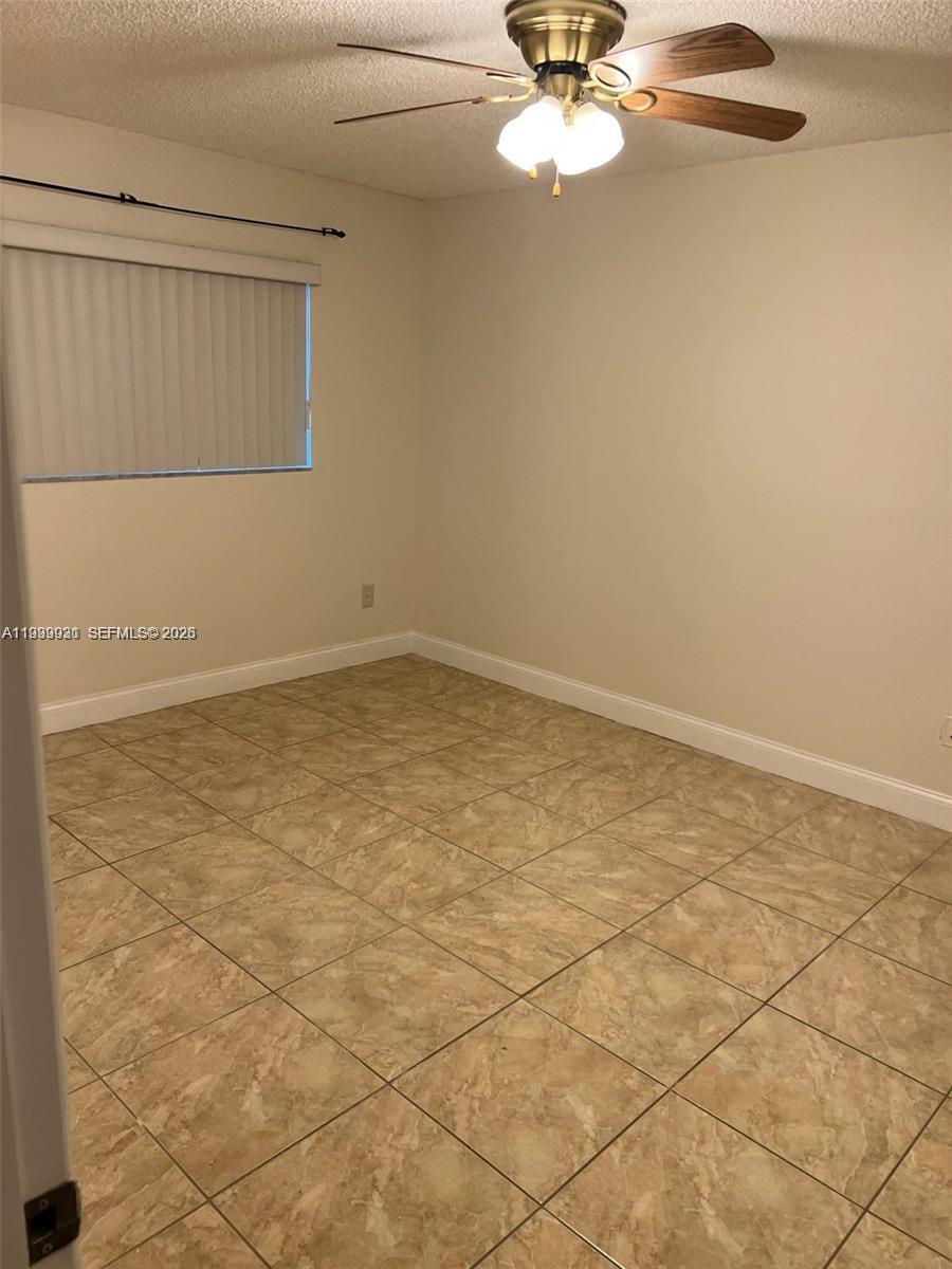 18210 Mediterranean Boulevard, Unit 620 Hialeah, FL 33015 - Photo 16 of 27 an empty room with a chandelier fan and windows