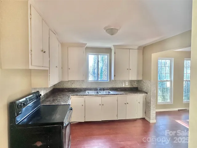 a kitchen that has a sink a stove and cabinets