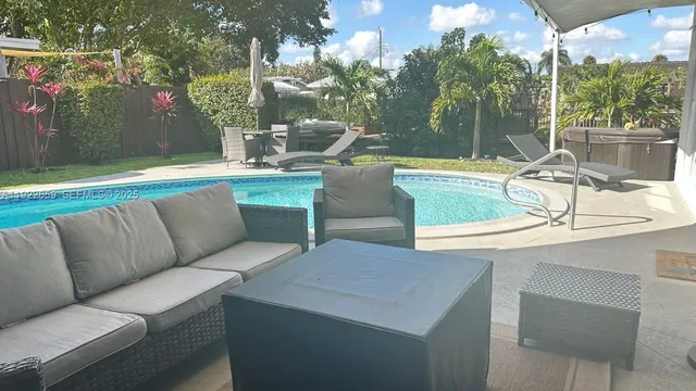 a view of a backyard with swimming pool and sitting area