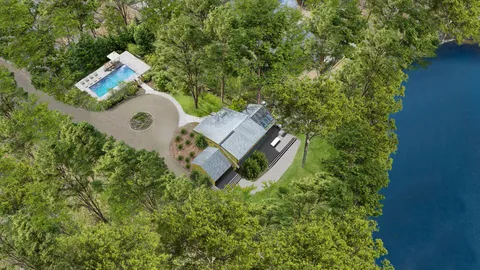 an aerial view of a house with outdoor space and trees all around