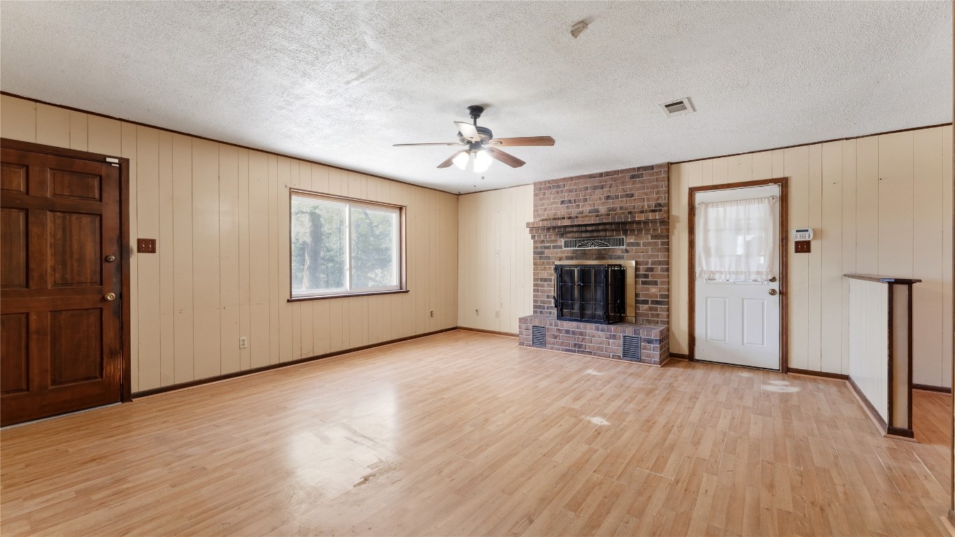 187 Watson Lake Road Huntsville, TX 77340 - Photo 12 of 25 an empty room with wooden floor fireplace and windows