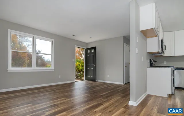 a view of an empty room with wooden floor and a window