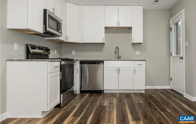 a kitchen with a sink a stove top oven and white cabinets