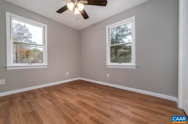 a view of an empty room with wooden floor and window