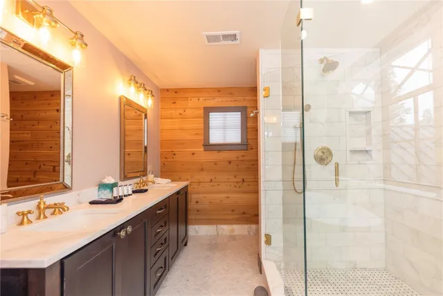 a bathroom with a double vanity sink mirror and shower