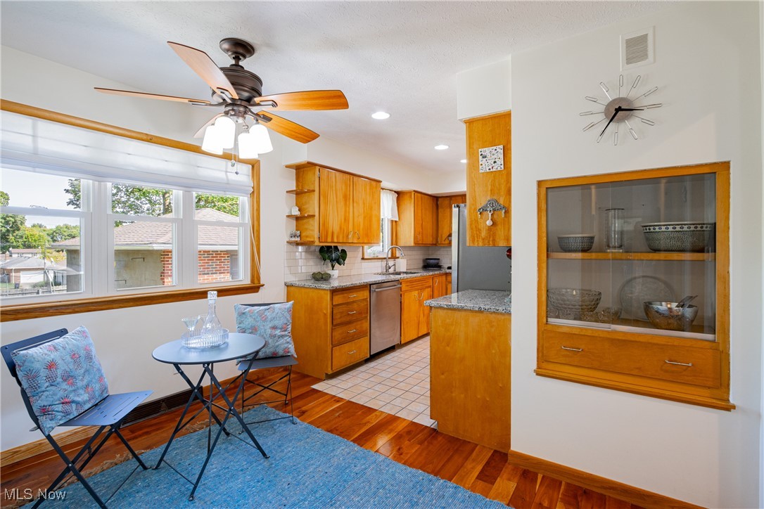 Kitchen featuring stainless steel appliances, light wood-type flooring, ceiling fan, and tasteful backsplash