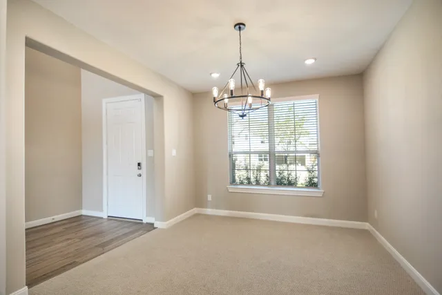 a view of empty room with wooden floor and chandelier
