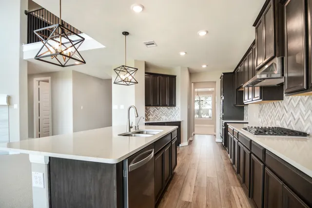 a kitchen with stainless steel appliances granite countertop a sink a stove and a wooden floors