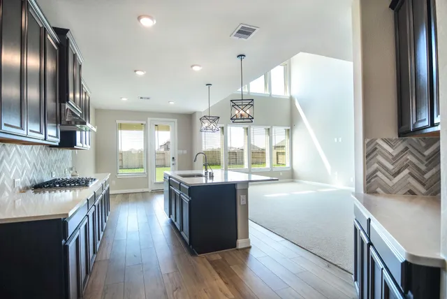 a kitchen with granite countertop a stove a sink a refrigerator and wooden floor