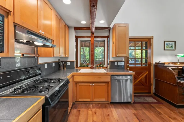 a kitchen with a stove a sink and wooden floor