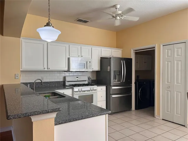 a kitchen with stainless steel appliances granite countertop a sink a refrigerator a stove a microwave and island