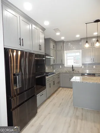 a modern kitchen with stainless steel appliances granite countertop a refrigerator a sink and a stove