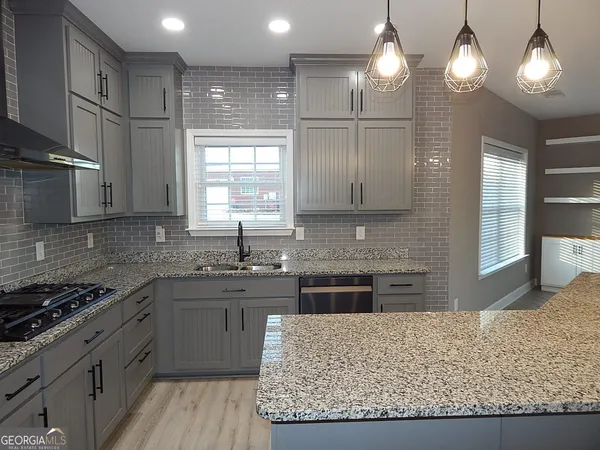 a kitchen with stainless steel appliances granite countertop wooden cabinets a stove a sink and a refrigerator