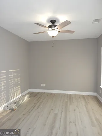an empty room with wooden floor fan and windows