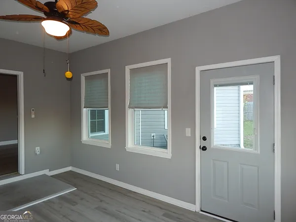 a view of an empty room with a window and wooden floor