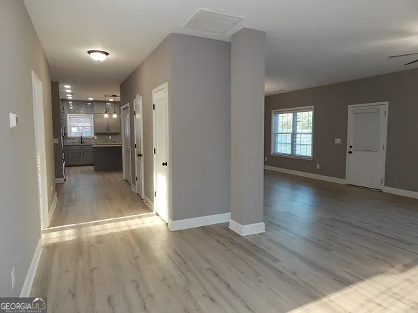 a view of a hallway with wooden floor and a living room