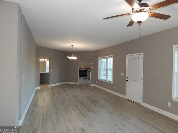 a view of an empty room with window and wooden floor