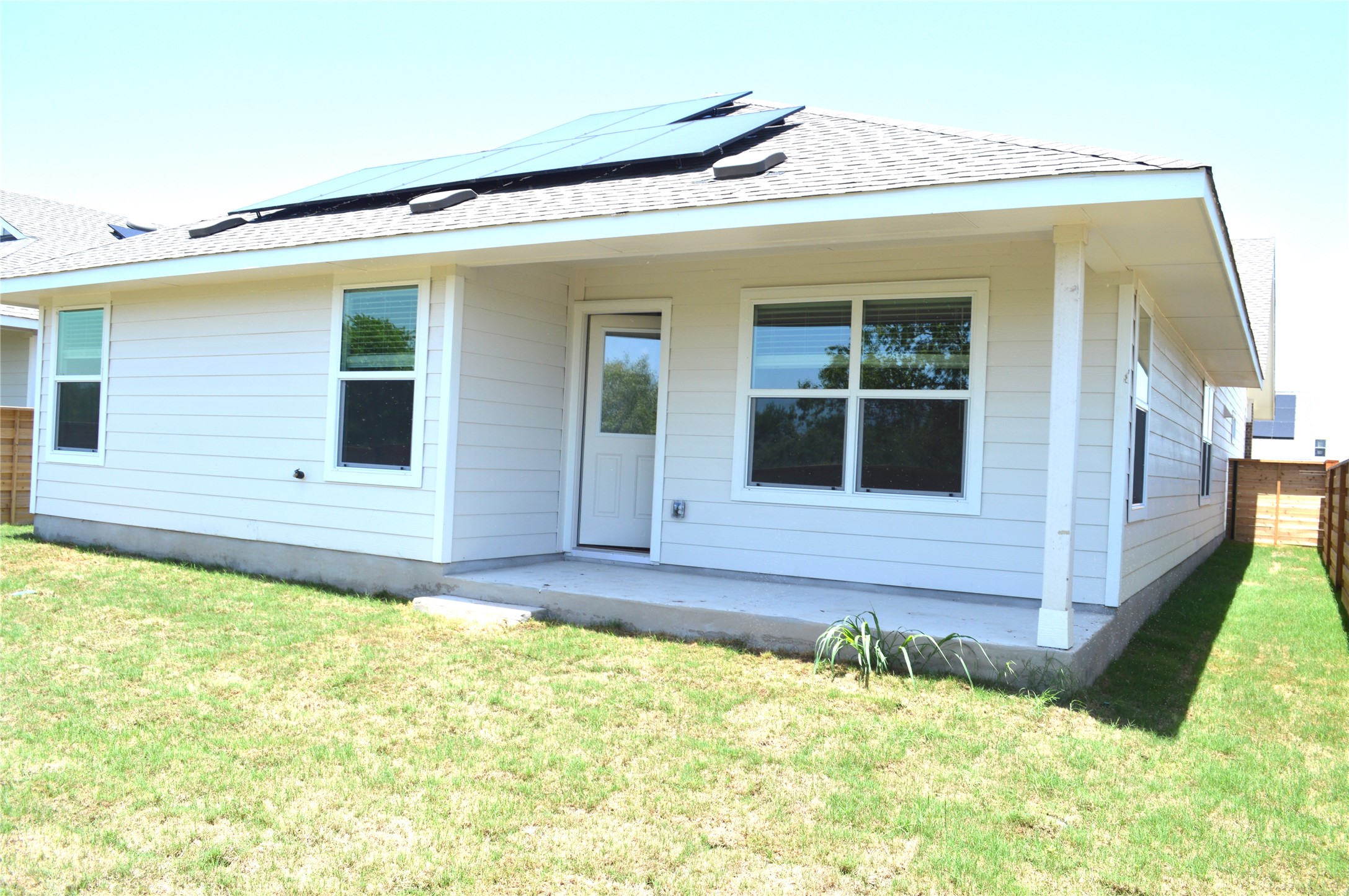 1524 Marley Kyle, TX 78640 - Photo 20 of 22 Rear view of house featuring roof with shingles, solar panels, and a patio area