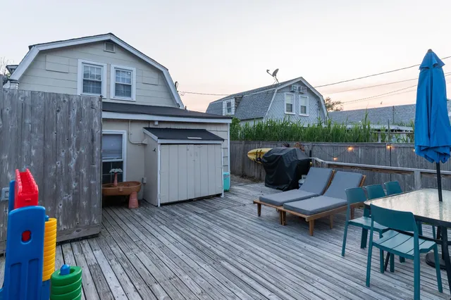 a terrace of a house with wooden floor outdoor seating and kitchen view