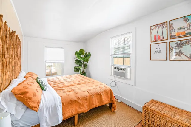 a bedroom with a bed painting on wall and a large window