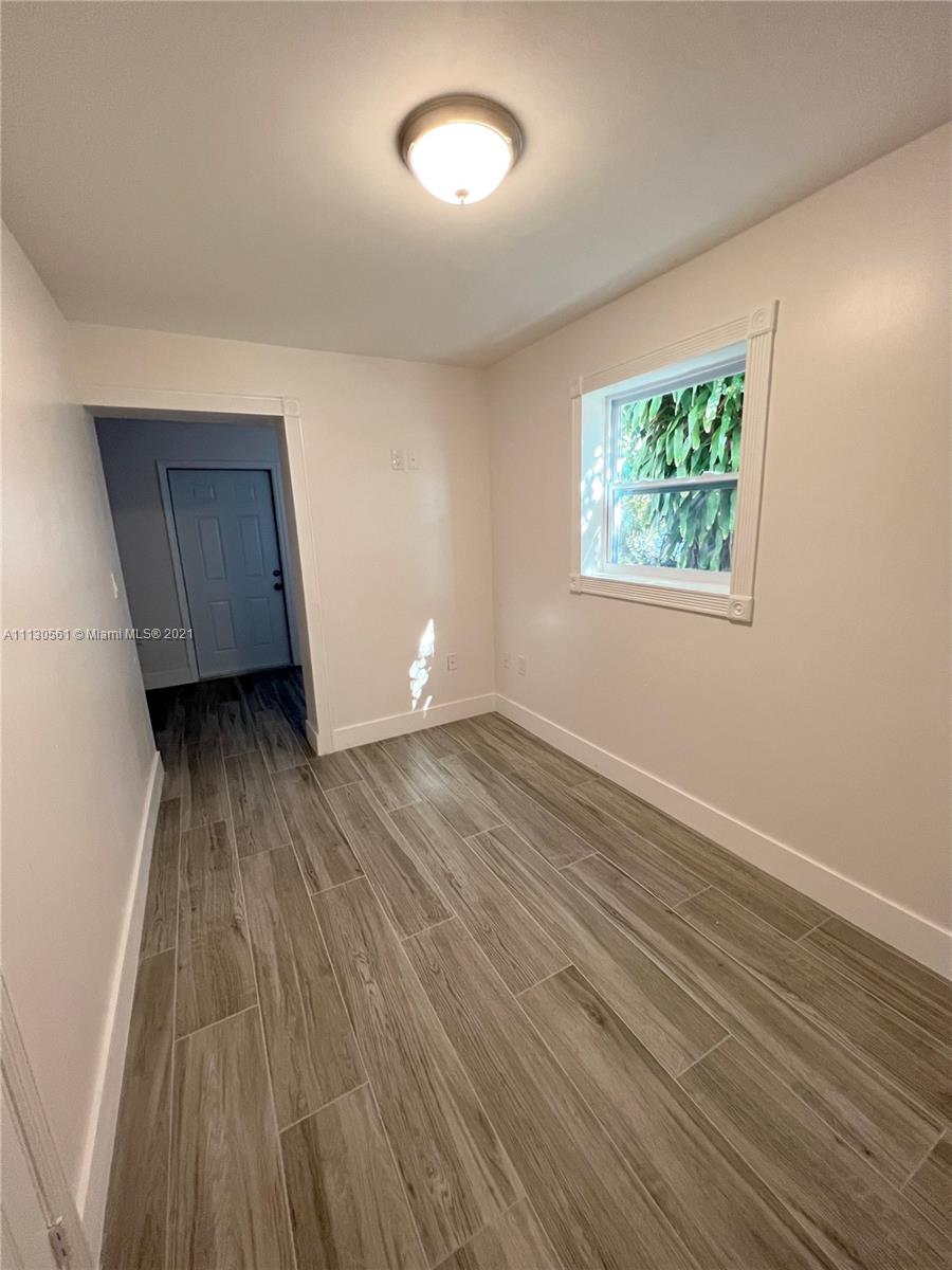 8935 Southwest 38th Street Miami, FL 33165 - Photo 14 of 24 an empty room with wooden floor and windows