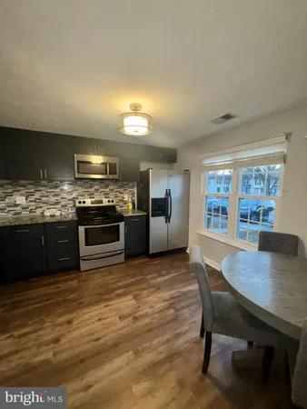 a kitchen with stainless steel appliances wooden floor dining table and chairs