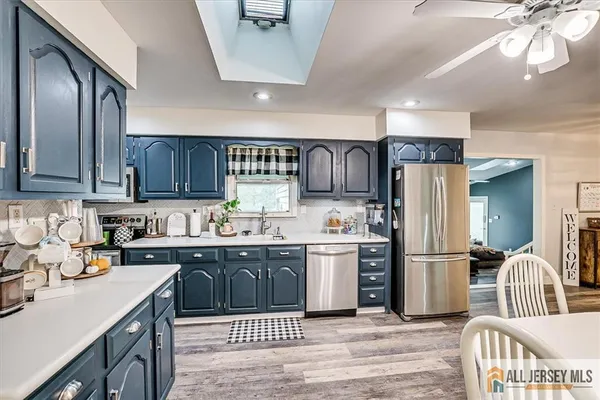 a kitchen with stainless steel appliances granite countertop a refrigerator a sink dishwasher a stove and a dining table with wooden floor