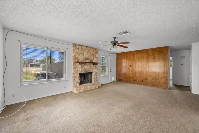 an empty room with windows and fireplace