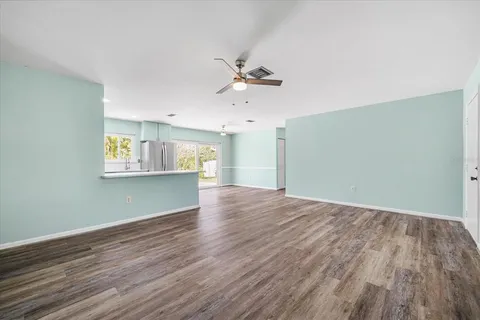an empty room with wooden floor ceiling fan and windows