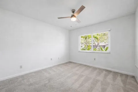 an empty room with windows and ceiling fan