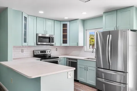 a kitchen with a refrigerator a microwave a sink and cabinets