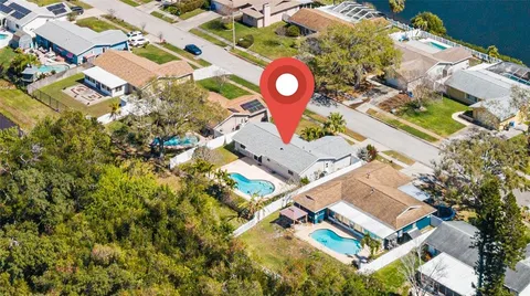 an aerial view of residential house with outdoor space and trees all around