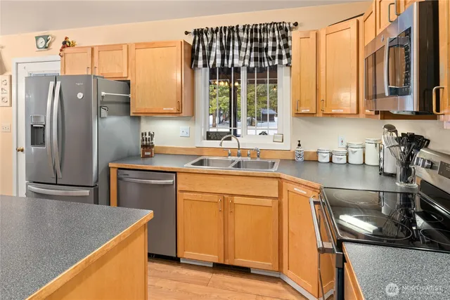 a kitchen with stainless steel appliances granite countertop a sink a refrigerator and a stove